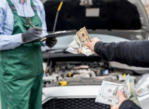 A close up of a person handing a mechanic money to fix their car