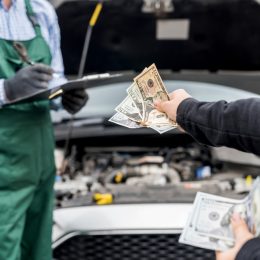 A close up of a person handing a mechanic money to fix their car