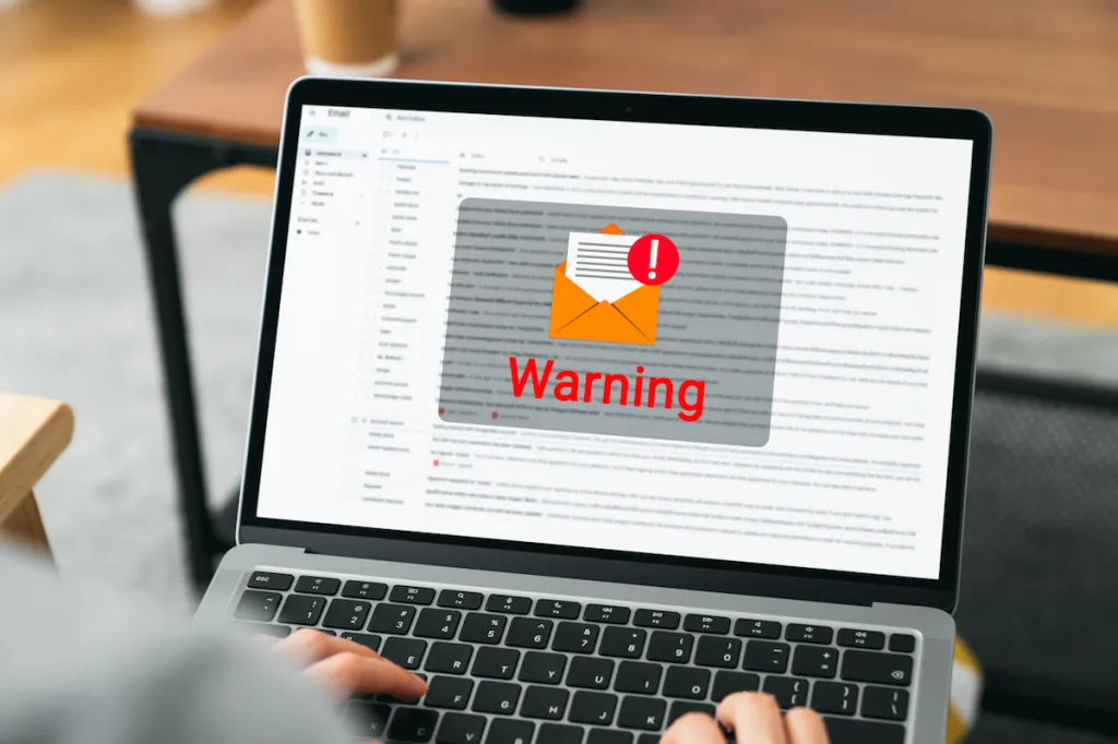 Laptop screen shows warning email message