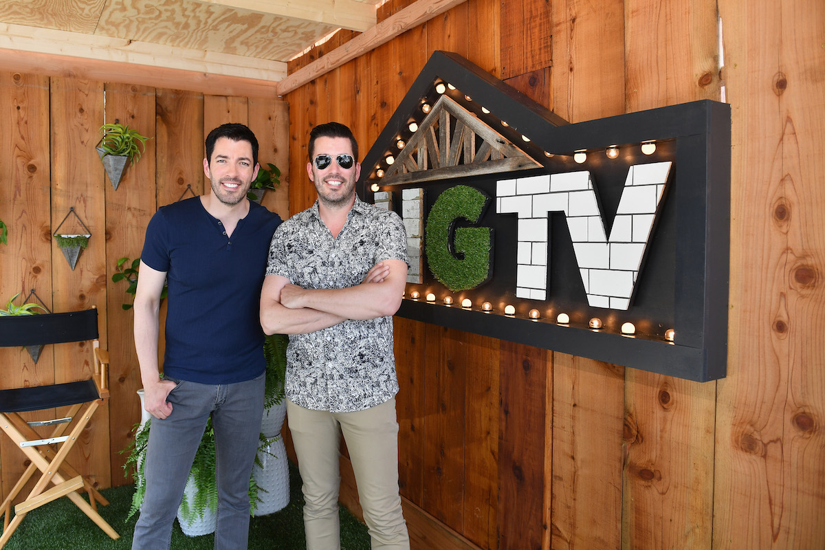 The Property Brothers, Drew and Jonathan Scott, posing for a photo in front of an HGTV sign