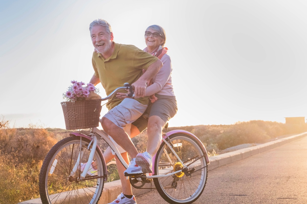joyful older married couple riding tandem bike