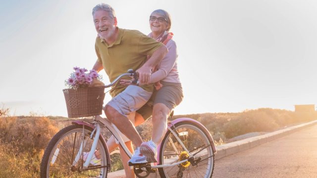 joyful older married couple riding tandem bike