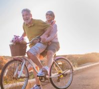 joyful older married couple riding tandem bike