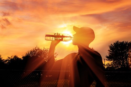 man drinking a bottle of water during heatwave