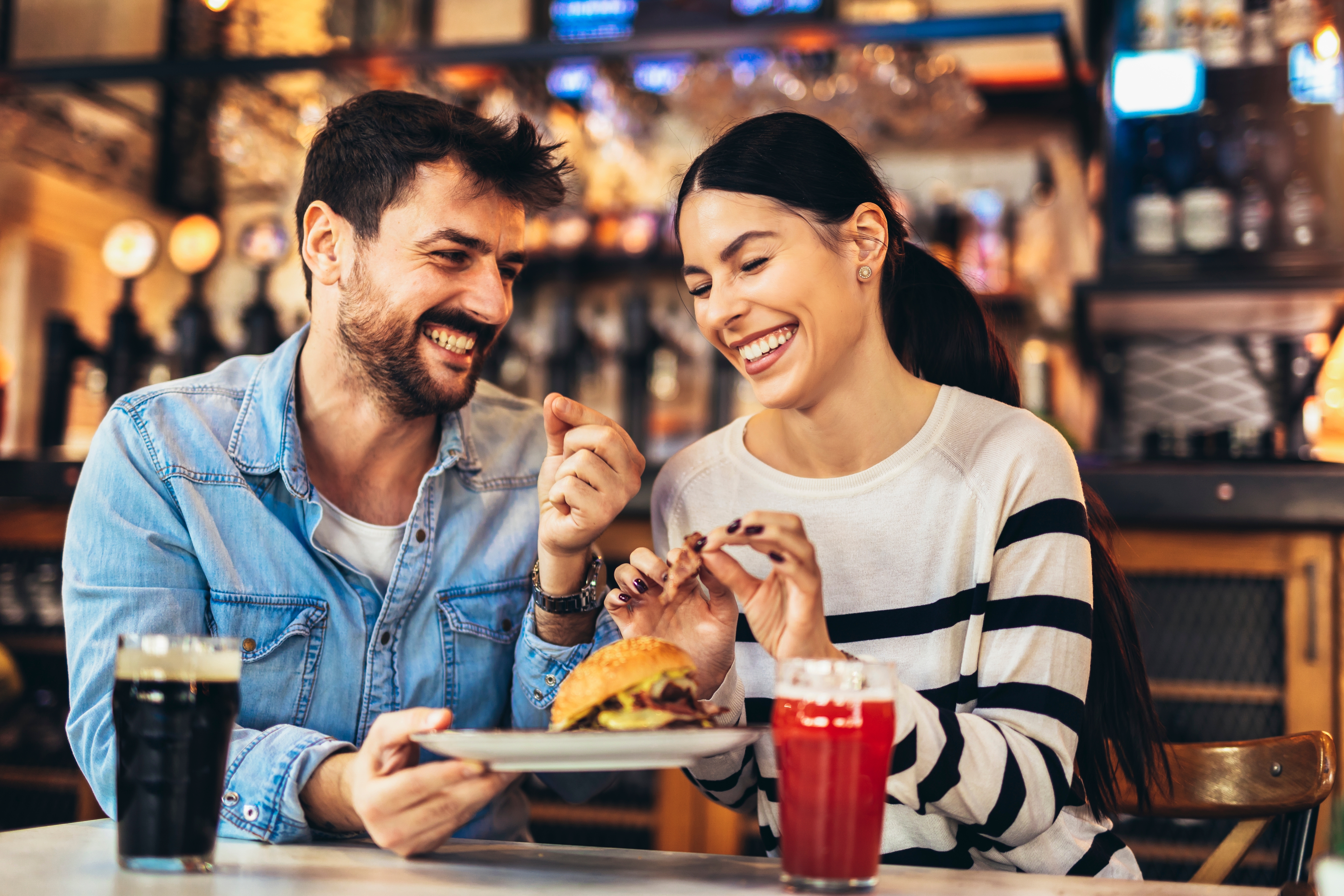 Young happy couple laughing on dinner date at restaurant