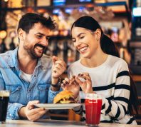 Young happy couple laughing on dinner date at restaurant