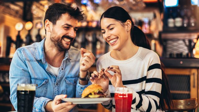 Young happy couple laughing on dinner date at restaurant