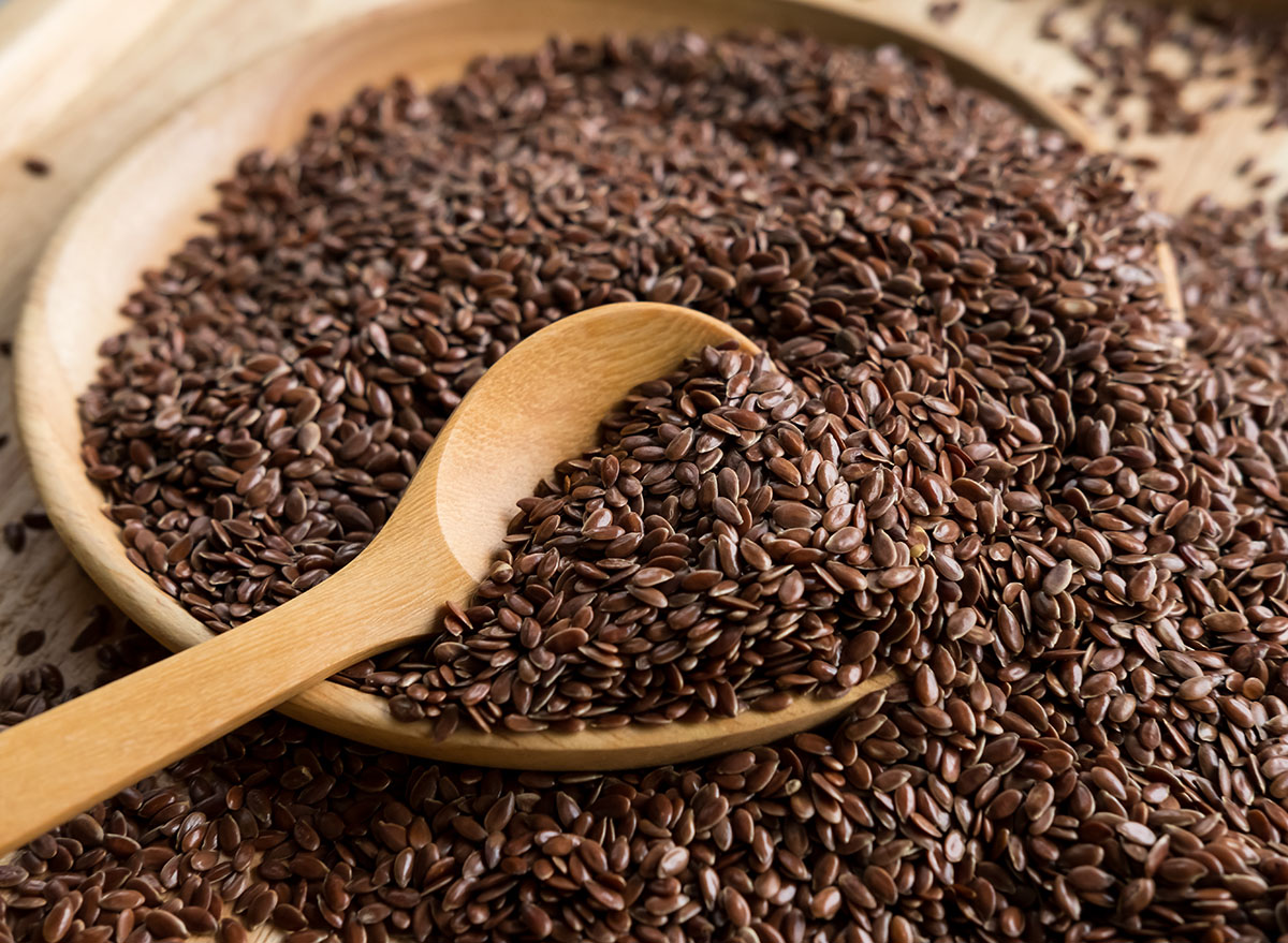Brown flaxseed in a wooden bowl with a wooden spoon