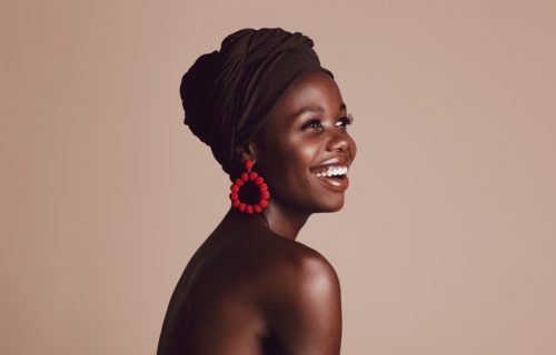 Close up of smiling woman on beige background. Beautiful female model with a cloth wrapped on head looking away and smiling.