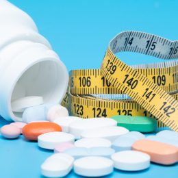 Tape measure and pills on a blue background