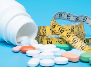 Tape measure and pills on a blue background