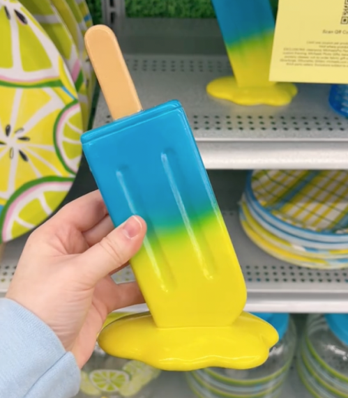 shopper holding up blue and yellow popsicle decor at Michaels