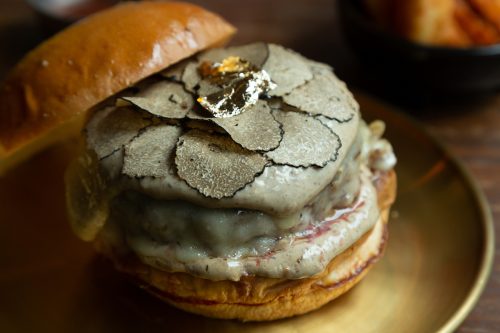 Hamburger topped with slice black truffles and swiss cheese