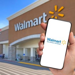 Walmart retailer delivery application on smartphone holding by hand with blurry Walmart store in the background
