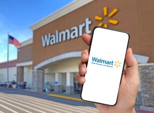 Walmart retailer delivery application on smartphone holding by hand with blurry Walmart store in the background