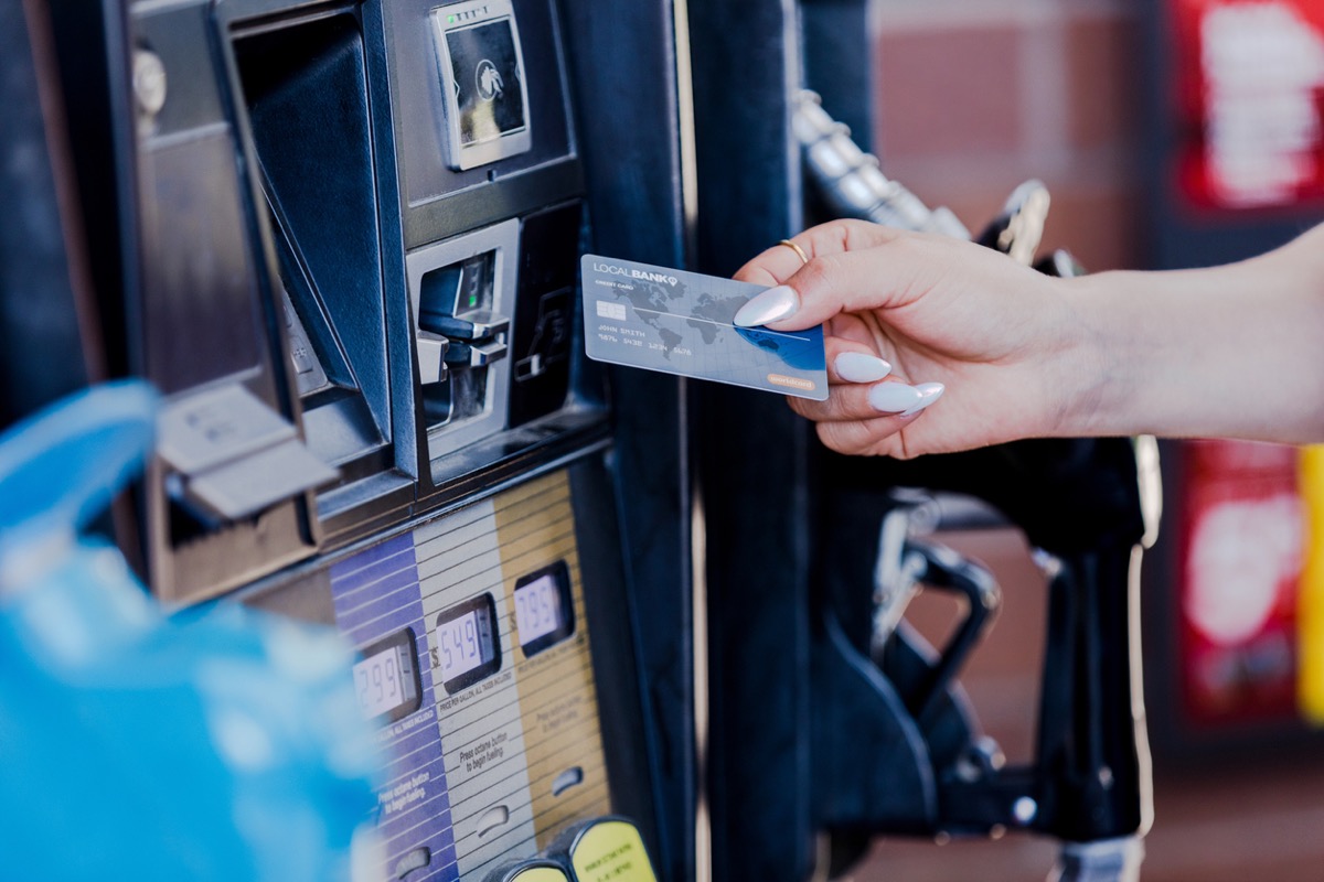 The focus of the photo is on a woman's nicely manicured hand as she prepares to pay for gas at the pump.