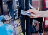 The focus of the photo is on a woman's nicely manicured hand as she prepares to pay for gas at the pump.