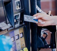The focus of the photo is on a woman's nicely manicured hand as she prepares to pay for gas at the pump.