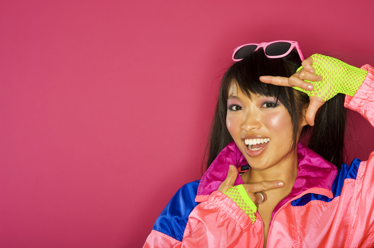 woman wearing 80s outfit voguing against pink background