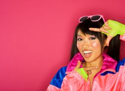 woman wearing 80s outfit voguing against pink background