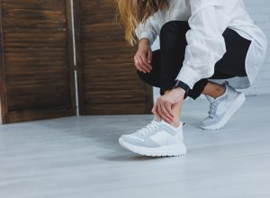 Woman kneeling down fixing her sneaker