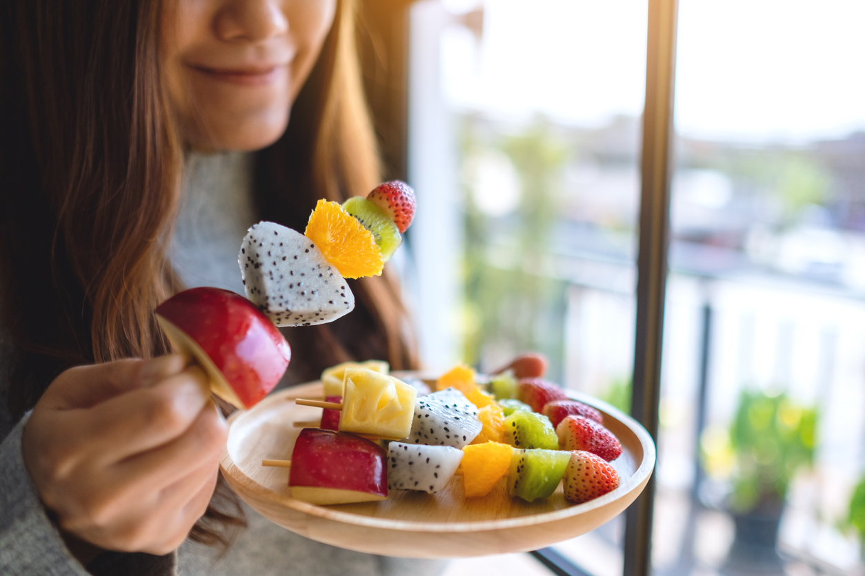 A close up of a person eating fruit skewers