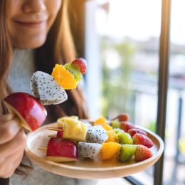A close up of a person eating fruit skewers