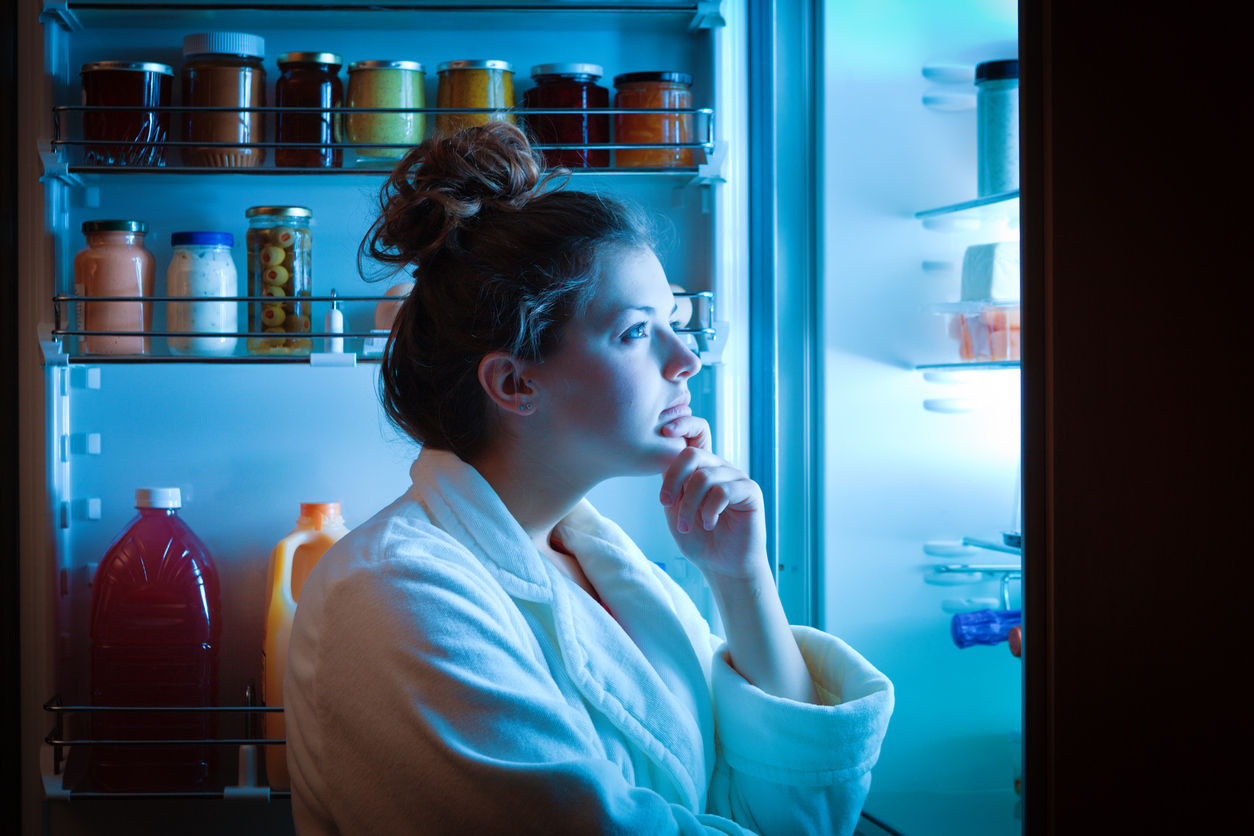 A woman looking into a fridge at night