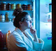 A woman looking into a fridge at night