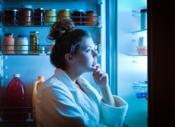 A woman looking into a fridge at night