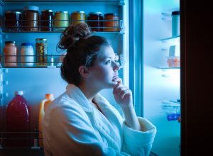 A woman looking into a fridge at night