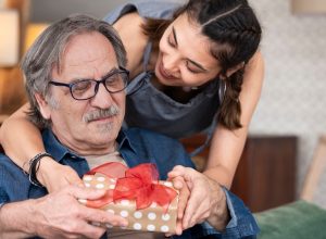 A woman giving a senior man a wrapped present