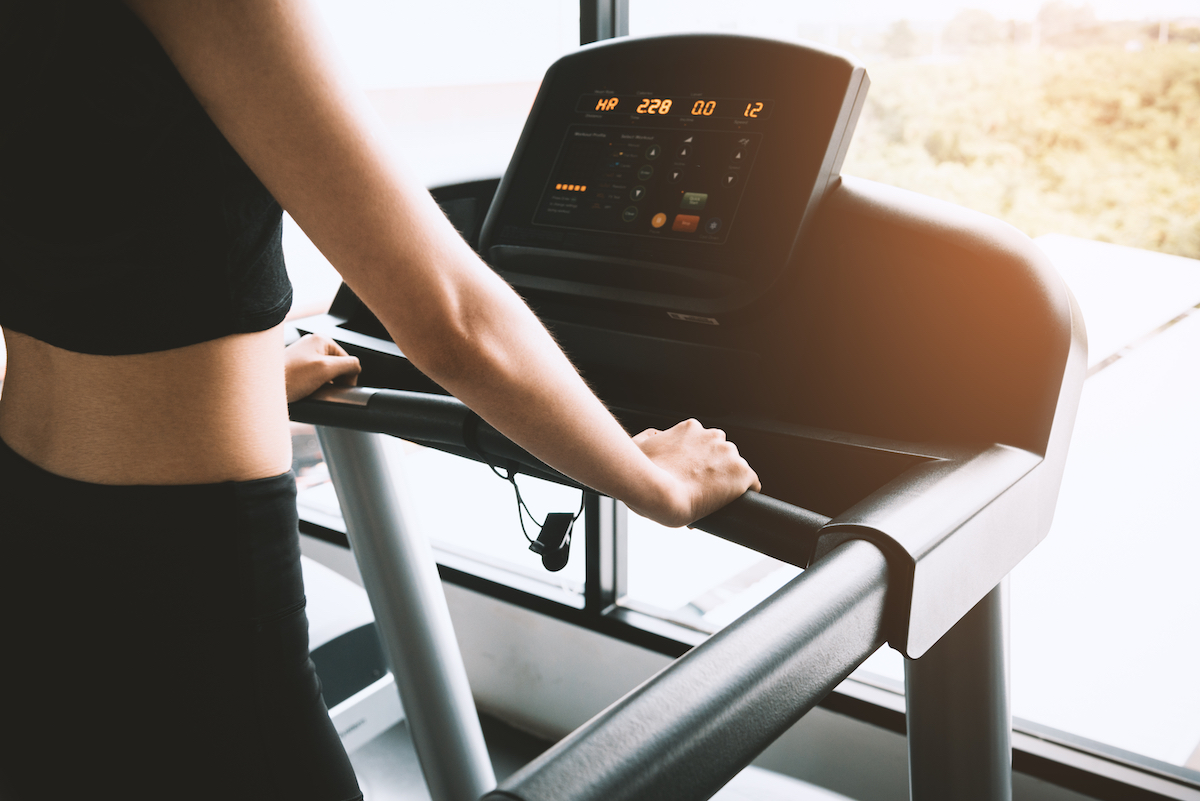 Woman wearing black workout clothes on a treadmill looking at stats on the screen