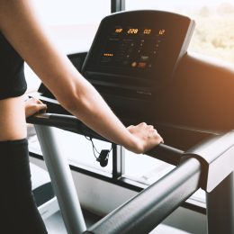 Woman wearing black workout clothes on a treadmill looking at stats on the screen