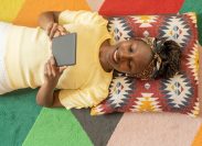 A woman lying down and reading a Kindle e-reader