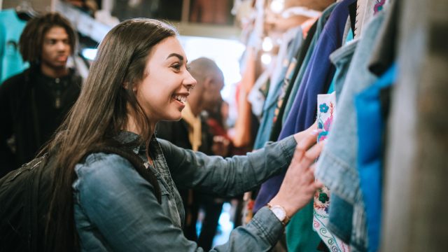 A woman looking through the racks at a thrift store