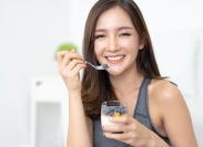 Healthy Diet And Nutrition. Portrait of happy beautiful young Asian woman eating natural yogurt at home and looking at camera.Weight Loss Food Concept. High Resolution