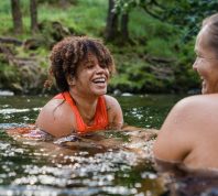 Women swimming in a river with friends