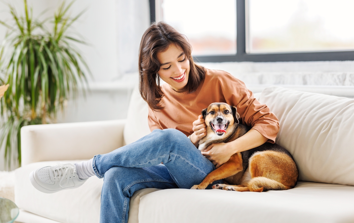 happy young woman holding her dog on the couch