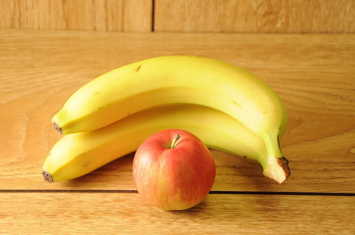 bananas and apple on wood surface