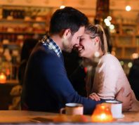 Happy couple kissing at bar and having date