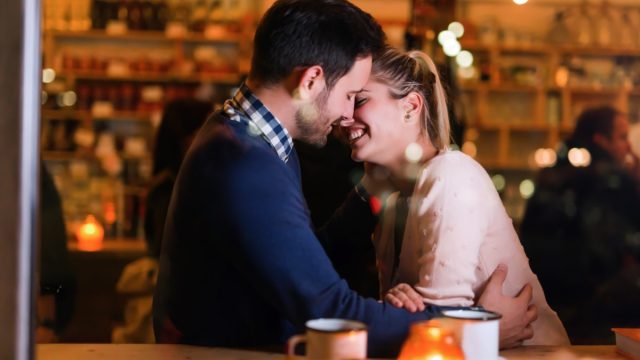 Happy couple kissing at bar and having date