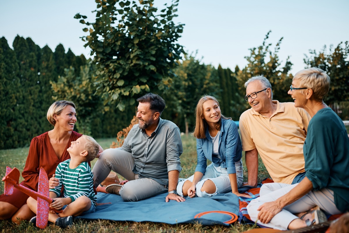 Happy extended family enjoying in conversation while relaxing in their backyard