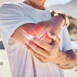 Man, joint pain and elbow arthritis in outdoor closeup in summer sunshine with massage arms. Broken arm, bone and guy at urban park in metro, city or town with physical therapy with hands in zoom