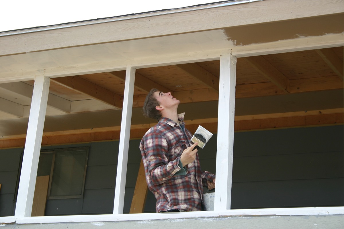 Young man painting porch white