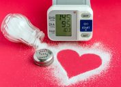 spilled salt shaker forming a heart, alongside a blood pressure monitor on a red background