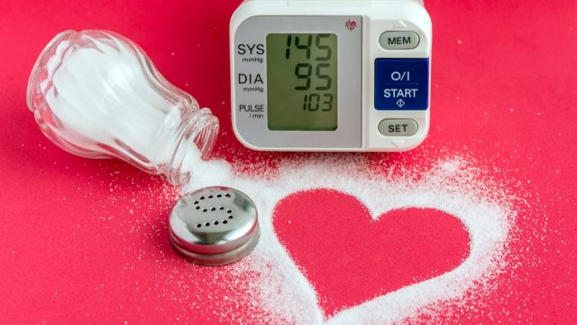 spilled salt shaker forming a heart, alongside a blood pressure monitor on a red background