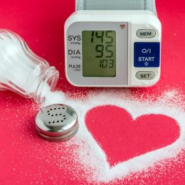 spilled salt shaker forming a heart, alongside a blood pressure monitor on a red background