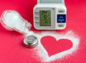 spilled salt shaker forming a heart, alongside a blood pressure monitor on a red background