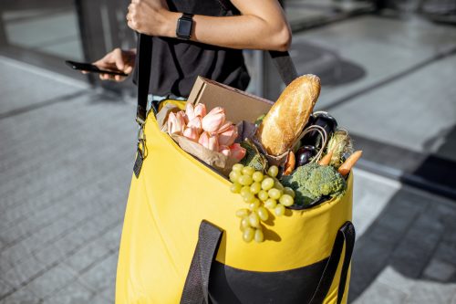 Woman carrying a yellow grocery bag filled with produce